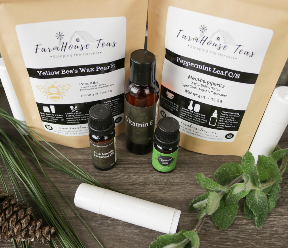 Farmhouse Teas products including tea bags, essential oils, and lip balm on a wooden surface with greenery.