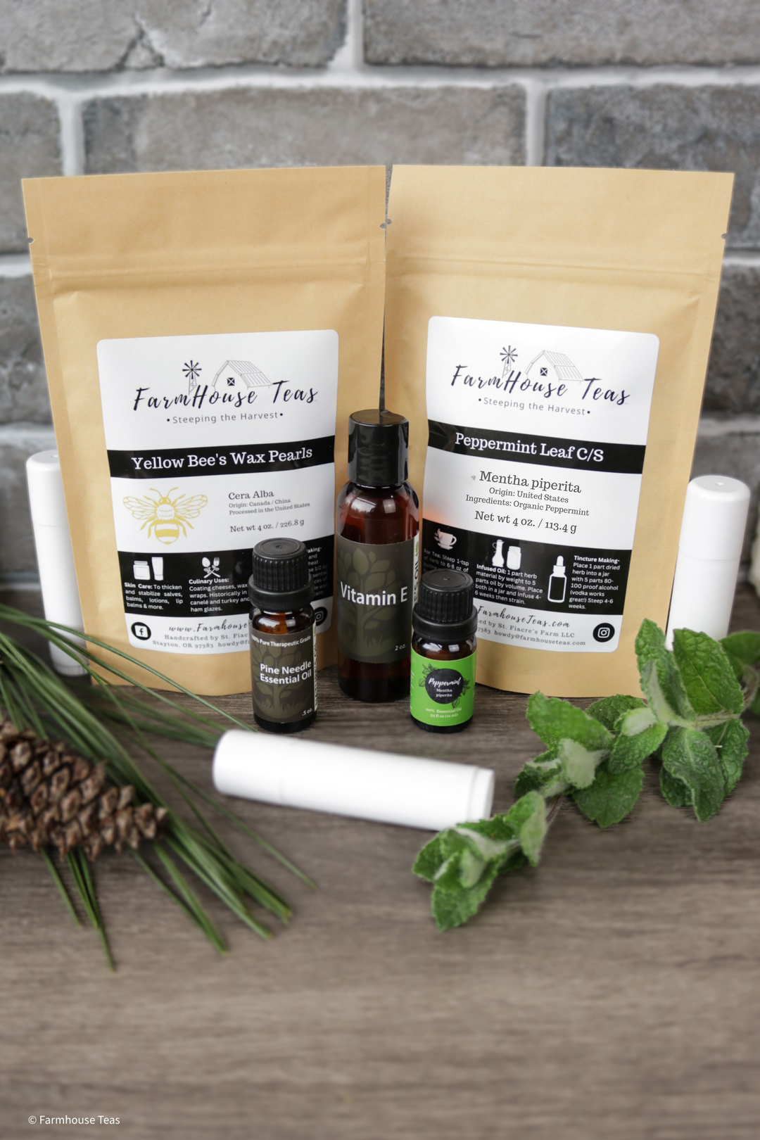Farmhouse Teas packages with tea bags, bottles, and candles on a wooden surface.