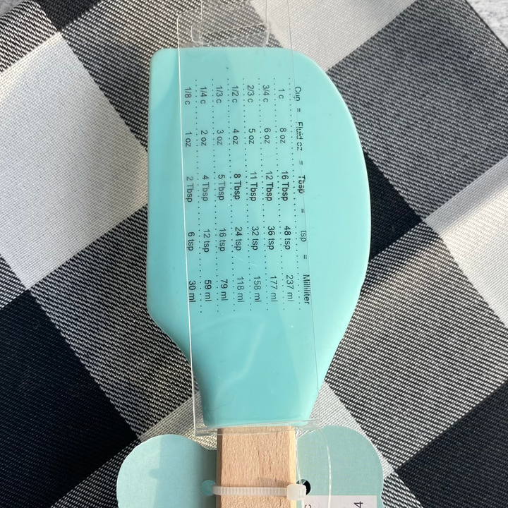 Teal spatula with wooden handle on a checkered cloth