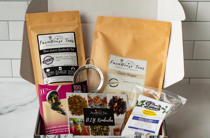 Collection of Farmhouse Teas products including tea bags, a strainer, and packets on a white surface.