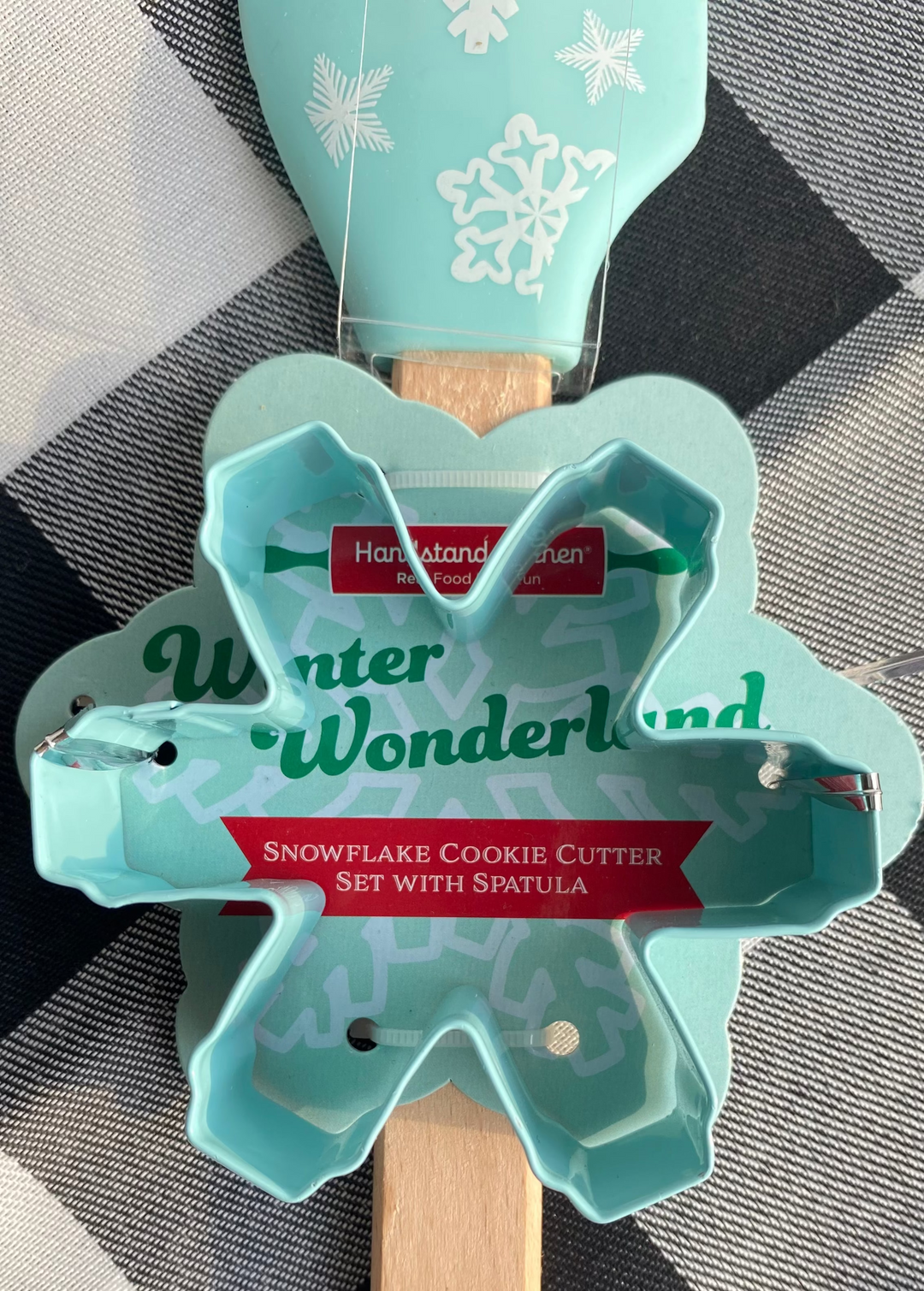 Snowflake cookie cutter set with spatula on a checkered background